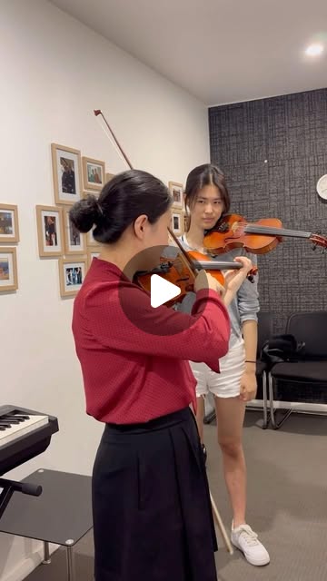 A teacher guiding a student playing violin.