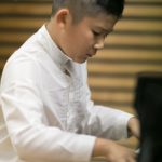 A young pianist concentrating at the keyboard during a performance.